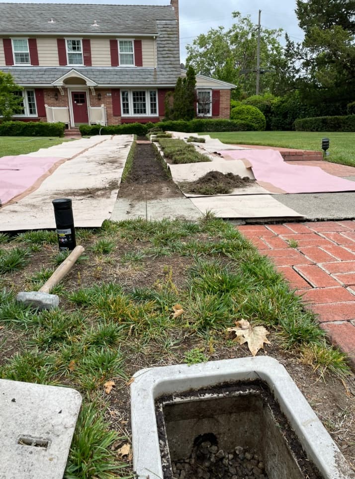 Front-yard sewer line replacement in progress with the lawn carefully protected by covers