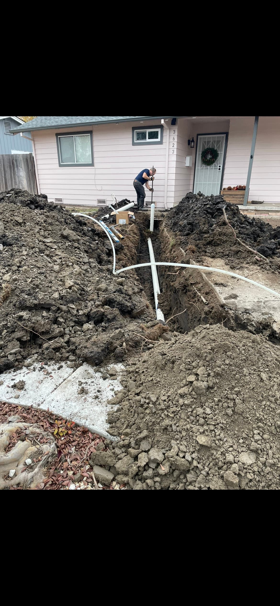 Plumber working in a front-yard trench during a sewer line repair in Santa Rosa